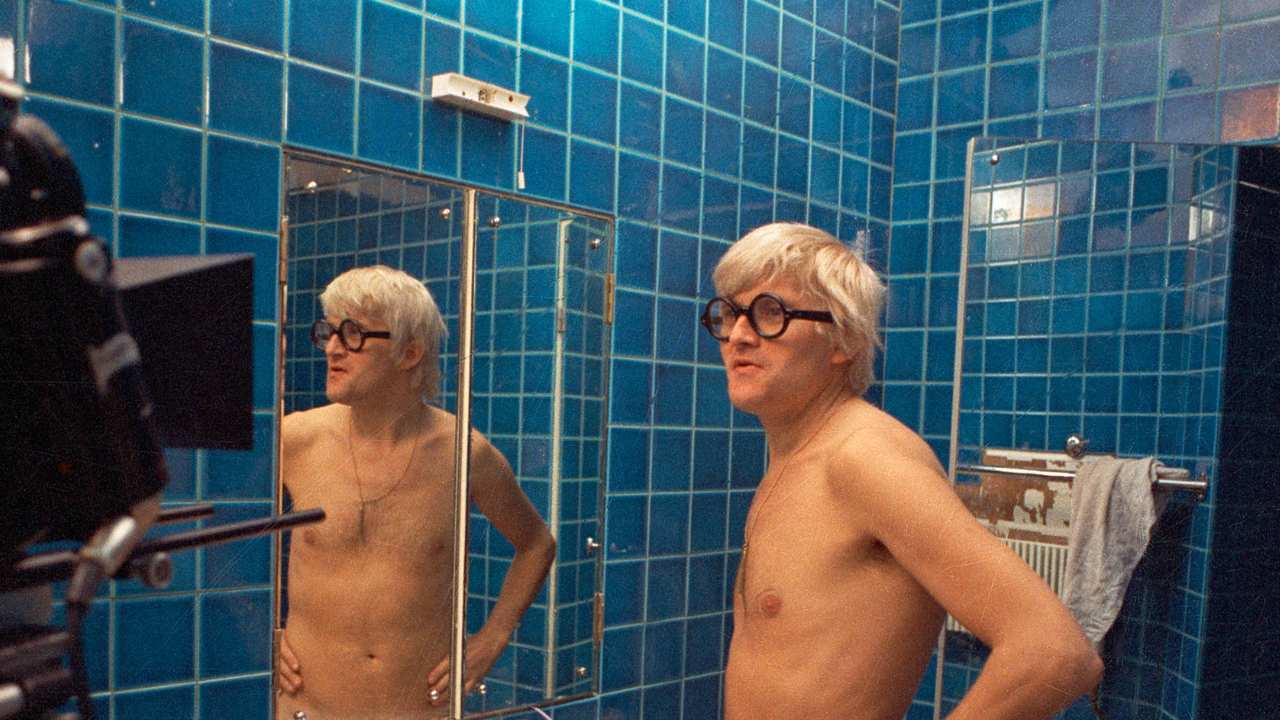 David Hockney in the bathroom in front of a mirror